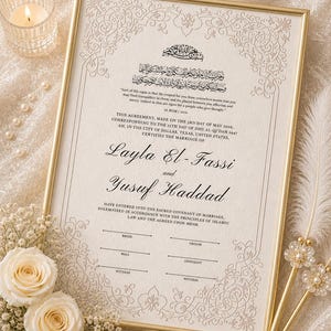 Könnte beinhalten: Eine gerahmte Heiratsurkunde mit goldenem Rand, mit den Namen Layla El-Fassi und Yusuf Haddad. Das Dokument enthält arabische Schrift und englischen Text, umgeben von floralen Verzierungen. Eine brennende Kerze, Rosen und dekorative Stifte vervollständigen die elegante Anordnung.