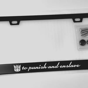 Peut inclure: Cadre de plaque d'immatriculation noir avec le texte "to punish and enslave" et un graphisme. Comprend le matériel de montage. Le cadre est rectangulaire avec des coins arrondis et deux trous de montage.