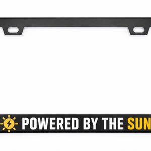 May include: A rectangular black number plate surround with rounded corners and two mounting holes at the top. The bottom edge features a yellow sun icon with a lightning bolt in the centre, followed by the white and yellow text POWERED BY THE SUN.