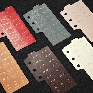 May include: Five rectangular planner dividers in red, grey, light pink, tan, and dark brown, each featuring three punched holes on the left side and gold foil-stamped numbers from 01 to 12, along with the words Title and Memo printed at the bottom.
