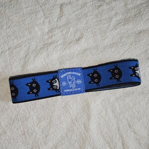 May include: A blue elastic headband featuring a repeating pattern of black cat silhouettes. A central blue fabric label displays the text "BENSTORE DESIGN EST. 2013 SENPOO.LTD.CO" along with a small white graphic of a dog standing in profile.