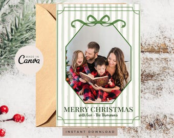 May include: A rectangular Christmas greeting card featuring a vertical light green striped background with a dark green border and a bow at the top. A central hexagonal frame displays a family reading a book. Text reads MERRY CHRISTMAS with love - The Thompsons.