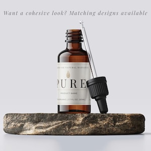 May include: A brown glass bottle with a white label that reads "PURE" and "ORGANIC 1.7 FL.OZ (50ML)". A dropper is next to the bottle. The bottle is on a stone. Text above the bottle reads "Want a cohesive look? Matching designs available."