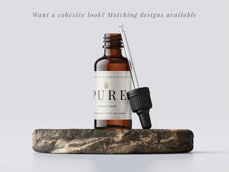 May include: A brown glass bottle with a white label that reads "PURE" and "ORGANIC 1.7 FL.OZ (50ML)". A dropper is next to the bottle. The bottle is on a stone. Text above the bottle reads "Want a cohesive look? Matching designs available."