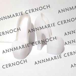 Peut inclure: Deux chaussures blanches &agrave; talons hauts en plastique. Les chaussures sont en plastique lisse et mat. Les chaussures sont toutes deux du m&ecirc;me style, mais l'une est l&eacute;g&egrave;rement plus grande que l'autre.