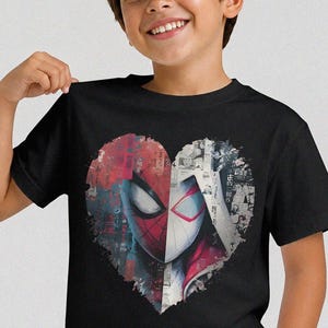 May include: A black short-sleeved t-shirt featuring a large heart-shaped graphic on the chest. The graphic is split down the middle, showing a red and black masked character on the left and a white and red masked character on the right.