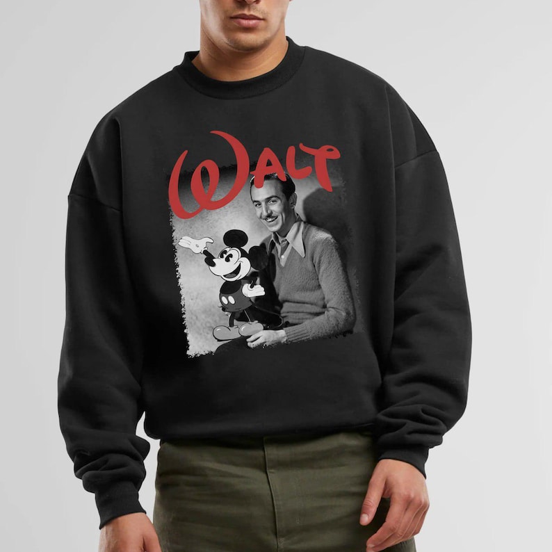 May include: Black sweatshirt with a black and white image of Walt Disney and Mickey Mouse, and the red word "Walt" above the image. The sweatshirt has a crew neck and long sleeves.