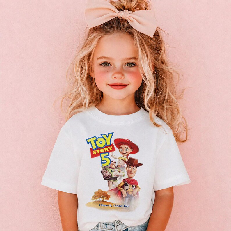 May include: A white short-sleeved t-shirt featuring a graphic print of Toy Story characters including Woody, Jessie, and Buzz Lightyear. The design includes the text Toy Story 5 and the phrase I Knew It, I Knew You above a small tree illustration.