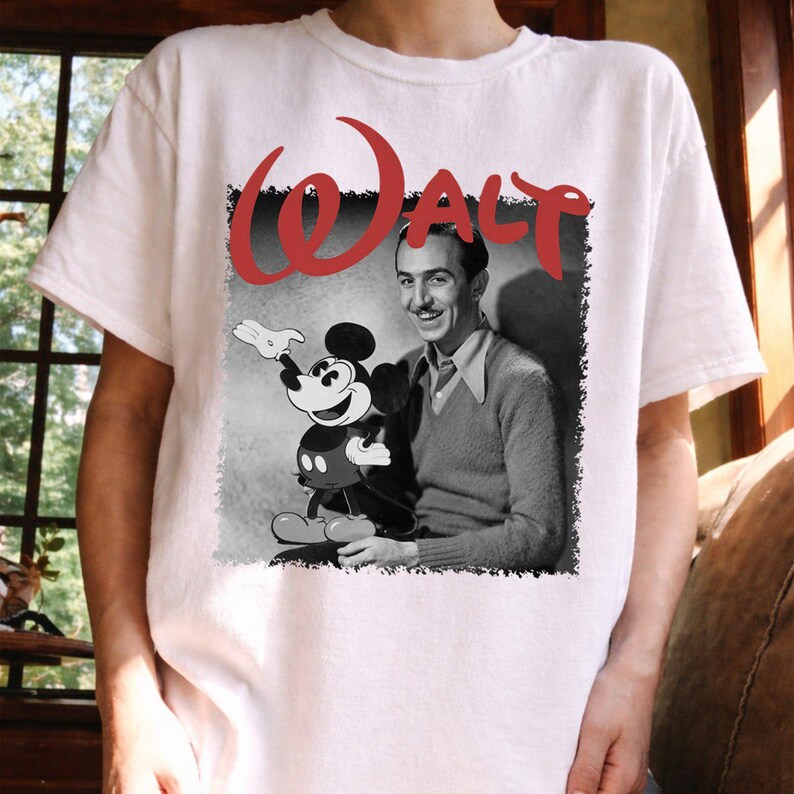 May include: White t-shirt with a black and white image of Walt Disney and Mickey Mouse. The word "WALT" is printed in red above the image. The shirt has a crew neck.