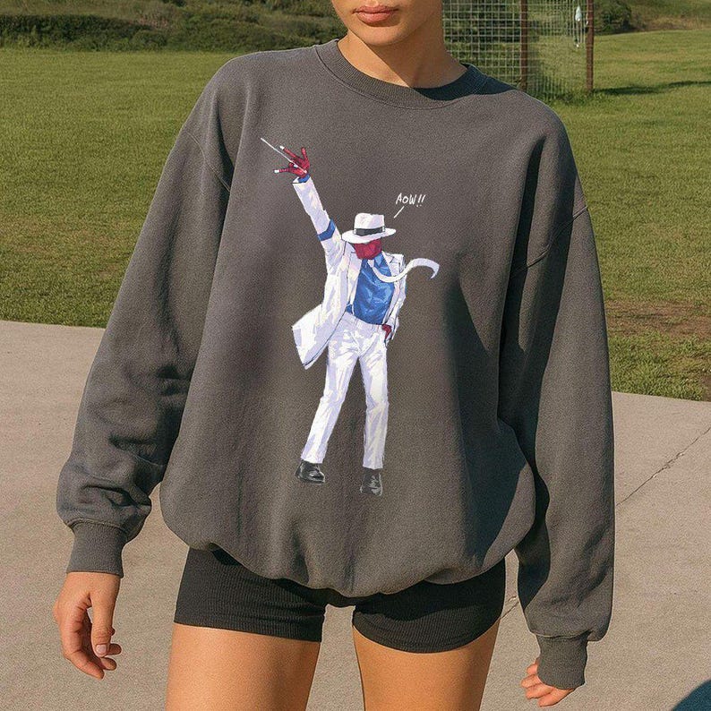 May include: A charcoal gray crewneck sweatshirt featuring a graphic print of a figure in a white suit, blue shirt, and white fedora, striking a dance pose with one arm raised. The graphic includes the text "AOW!!" in white lettering.