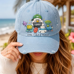 May include: A light blue distressed baseball cap featuring a graphic of a cartoon owl wearing a green cap and glasses, surrounded by a laptop, mouse, printer, and Wi-Fi icon. The text CTRL + ALT + TEACH is printed in black below the graphic.