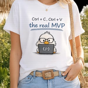 以下が含まれることがあります： 「Ctrl + C, Ctrl + V the real MVP」の文字がプリントされた白いTシャツ。メガネをかけたアヒルの漫画が、コード記号の入ったノートパソコンを持っています。アヒルは黄色と白です。シャツは半袖です。