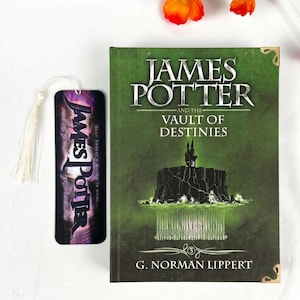 May include: A hardcover book titled James Potter and the Vault of Destinies by G. Norman Lippert with a green cover featuring a dark castle illustration, paired with a matching vertical bookmark that has a white tassel and purple text.