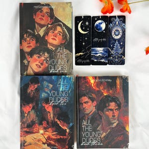 Op de afbeelding: Een verzameling boeken en bladwijzers met de titel "All The Young Dudes". De boekomslagen tonen illustraties van jonge mannen. De bladwijzers hebben hemelse ontwerpen met manen, sterren en een klok. Oranje bloemen zijn op de achtergrond.