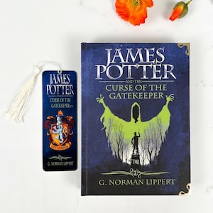 May include: A hardcover book titled James Potter and the Curse of the Gatekeeper by G. Norman Lippert with a blue cover featuring a green silhouette and a matching bookmark with a white tassel and a Gryffindor crest, accompanied by an orange flower.