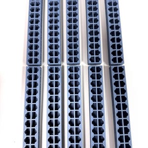 May include: Ten blue-gray rectangular plastic components with a grid of square holes. The components are arranged in two rows of five, against a white background. The objects appear to be 3D printed.