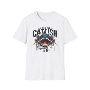 Könnte beinhalten: Weißes T-Shirt mit einer Grafik einer Wels mit offenem Maul. Der Text "I FISH FOR CATFISH EVERYTHING ELSE IS BAIT" ist oberhalb und unterhalb der Fischgrafik in fetter, schwarzer Schrift gedruckt. Das T-Shirt ist aus weichem Material.
