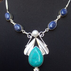 May include: A silver necklace with a turquoise pendant and blue oval stones. The pendant features a silver design with a pearl accent.