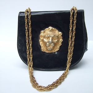 May include: A black patent leather handbag with a gold chain strap and a gold lion head design on the front.