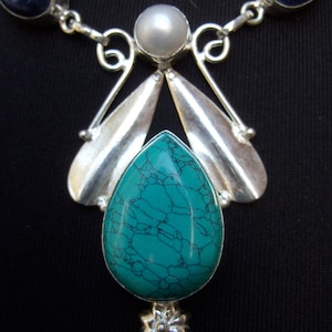 May include: A silver necklace with a turquoise pendant, a pearl, and two lapis lazuli stones.
