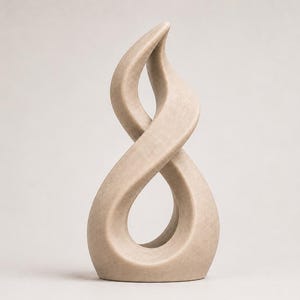 Op de afbeelding: Een beige sculptuur met een gladde, doorlopende gedraaide vorm die een open, lusvormige acht creëert. Het object heeft een matte afwerking en een solide, gebogen structuur die naar boven toe taps toeloopt en op een platte basis staat.