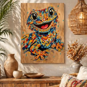 Op de afbeelding: Een kleurrijk schilderij van een gekko met een brede glimlach, weergegeven in een mozaïekstijl. Het kunstwerk heeft een levendig palet van blauw, oranje en geel op een houten paneel. De ogen van de gekko zijn groot en expressief.