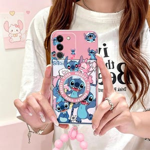 Pu&ograve; includere: Custodia per telefono rosa con il personaggio Stitch di Lilo & Stitch. Il design presenta Stitch in varie pose, con la scritta "Naughty Tiger". Include un anello di supporto e un cinturino da polso con perline rosa.