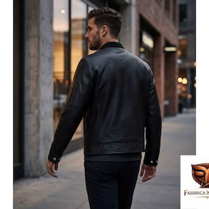 Puede incluir: Una chaqueta estilo bomber de color negro con un sutil patr&oacute;n texturizado, que presenta un cuello acanalado, mangas largas con pu&ntilde;os abotonados y un dobladillo recto. La chaqueta se lleva sobre una camisa oscura y pantalones oscuros, vista de espaldas.