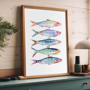 May include: A watercolor painting of five colorful fish, arranged vertically, with their tails facing the left side of the image. The fish are painted in shades of blue, green, pink, and purple, with white accents. The background is white.