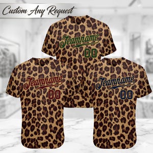 May include: Three short-sleeved baseball jerseys with a leopard print pattern. Each jersey has a different color of text that says "Teamname" and the number "00". The text "Custom Any Request" is at the top.