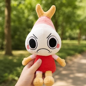 Puede incluir: Un peluche con forma de camar&oacute;n con una expresi&oacute;n de mal humor. El juguete tiene una cabeza blanca con ojos negros, mejillas rosadas y un vestido rojo. La cola y las extremidades del camar&oacute;n son amarillas.