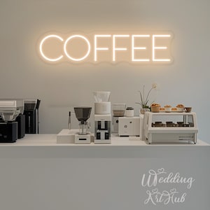 May include: A coffee shop setup with a neon sign that reads "COFFEE". The counter displays various coffee-making equipment, including grinders and pour-over devices. A display case holds pastries. The overall aesthetic is minimalist and modern.