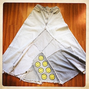 May include: A long denim skirt made from multiple pieces of denim, with a patchwork design and yellow smiley face patches.