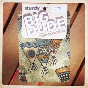 May include: Two iron-on patches with a geometric design in shades of brown, blue, and white. The patches are labeled "Big Dude" and "iron-on patches". The packaging is labeled "Sturdy Brand".