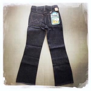 May include: A pair of dark blue denim jeans with a wide leg opening. The jeans have a label on the back pocket that says "Wrangler" and "Boot Cut".