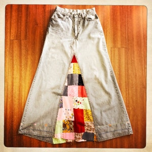 May include: A long denim skirt with a patchwork panel on the front. The panel is made of various colourful fabrics, including red, pink, yellow, and green.