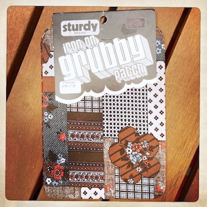 May include: A pack of three iron-on patches with a variety of brown, blue, and white patterned designs. The patches are labeled "Sturdy Brand Iron-On Grubby Patch" and "3 Patches 3 in x 4 in".