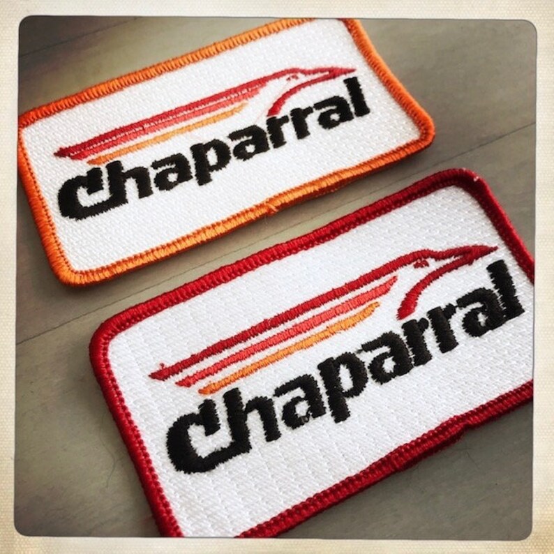 Puede incluir: Dos parches bordados con la palabra "Chaparral" en letras negras sobre fondo blanco. El parche superior tiene un borde naranja y el parche inferior tiene un borde rojo. Ambos parches presentan un dise&ntilde;o de p&aacute;jaro estilizado en naranja, rojo y amarillo.