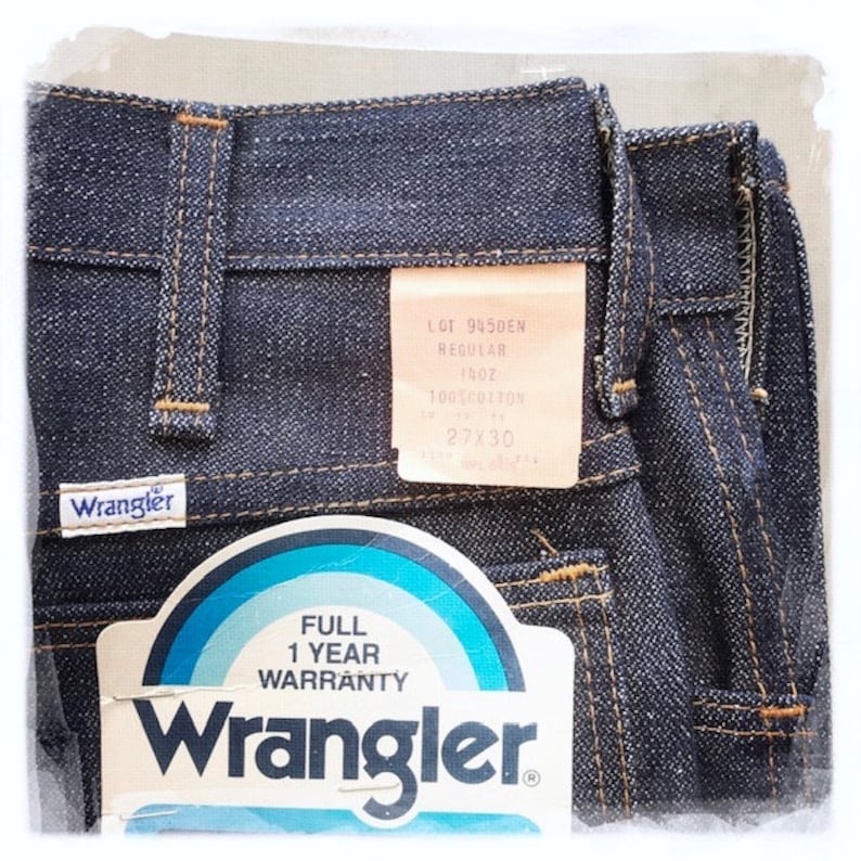 May include: A pair of dark blue denim jeans with a Wrangler label and a white tag with the text "LOT 9450EN REGULAR 140Z 100%COTTON 27X30" and a white tag with the text "FULL 1 YEAR WARRANTY Wrangler".