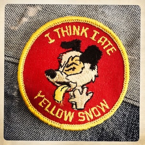 May include: A red and yellow embroidered patch with a cartoon dog and the text "I think I ate yellow snow".