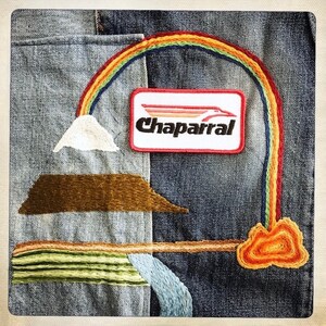 Puede incluir: Una chaqueta vaquera con detalles bordados, incluyendo un arco&iacute;ris, una monta&ntilde;a, una nube y un parche que dice "Chaparral".