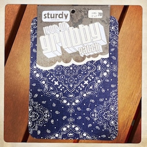 Puede incluir: Dos parches para planchar con un patrón paisley azul y blanco. Los parches están etiquetados como "Iron-on Grubby Patch" y "Sturdy Brand".