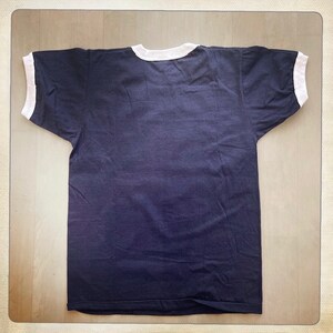 Op de afbeelding: Een donkerblauw t-shirt met witte boord en mouwen.