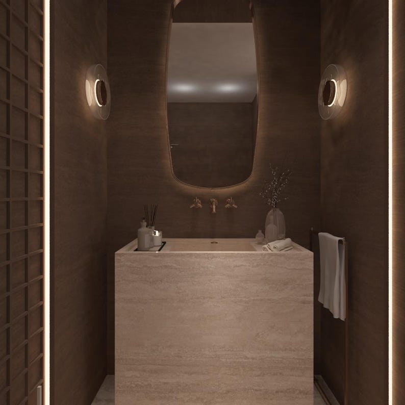 May include: A modern bathroom interior with a rectangular stone sink and a large, curved mirror. The walls are a dark brown, and the space is illuminated by soft lighting. Decorative items include a vase with greenery and a towel rack.