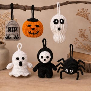 May include: A set of six crocheted Halloween ornaments including a grey tombstone with RIP text, an orange pumpkin, two white ghosts, a black and white hooded figure, and a black spider, each featuring a black yarn loop for hanging.