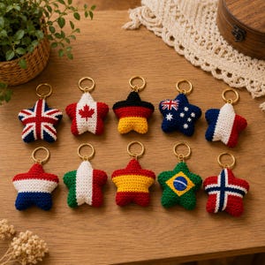 Puede incluir: Diez llaveros en forma de estrella hechos de hilo de ganchillo, cada uno con un diseño de bandera nacional diferente. Las banderas incluyen el Reino Unido, Canadá, Alemania, Australia, Francia, los Países Bajos, Italia, España, Brasil y Noruega. Cada uno tiene una anilla dorada.
