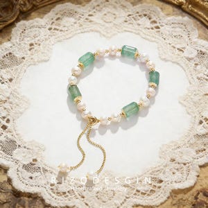 May include: A delicate bracelet featuring alternating green rectangular gemstones and white pearls, connected by gold-colored accents. The bracelet has a gold chain with a pearl at the end. The text "RIZODESGIN Handcrafted Jewellery" is at the bottom.