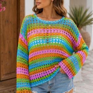 May include: A long-sleeved, loose-fitting sweater featuring a vibrant, multi-colored horizontal striped pattern in shades of pink, orange, green, and blue. The garment is crafted with an open-knit, crochet-style texture and a round neckline.