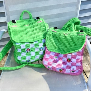 Puede incluir: Dos bolsos de crochet con un patrón a cuadros. Un bolso es verde con aplicaciones de setas y el otro es rosa con aplicaciones de fresas.