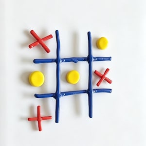 May include: A colorful tic-tac-toe game set against a white background. The game board is a vibrant blue, with red X's and yellow O's. This classic game is perfect for family fun and makes a great gift.
